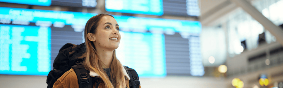 Une femme dans un aéroport devant les tableaux d'affichage